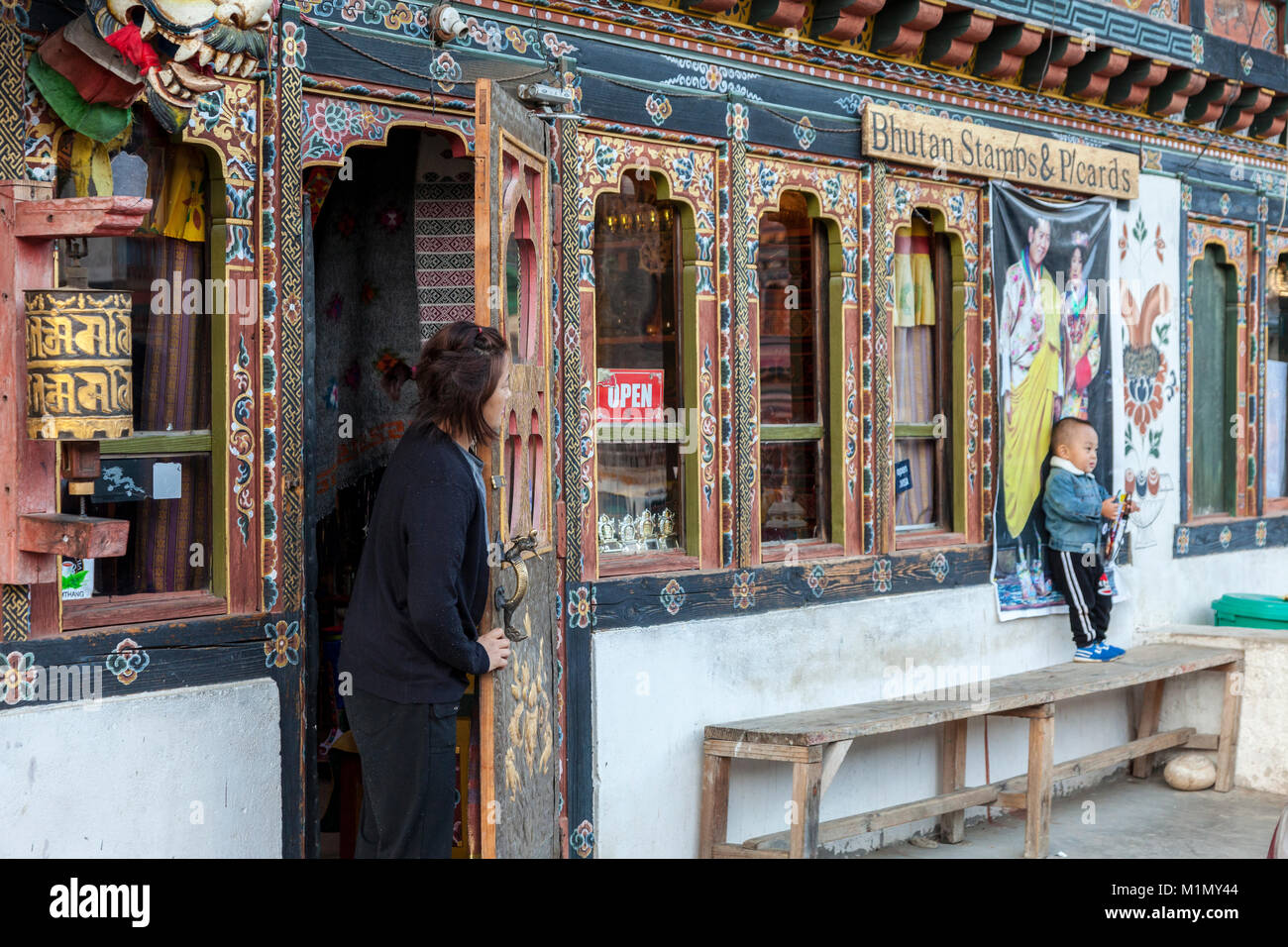 Jakar, Bumthang, Bhoutan. Woman Looking at petit garçon à l'extérieur de magasin. Banque D'Images