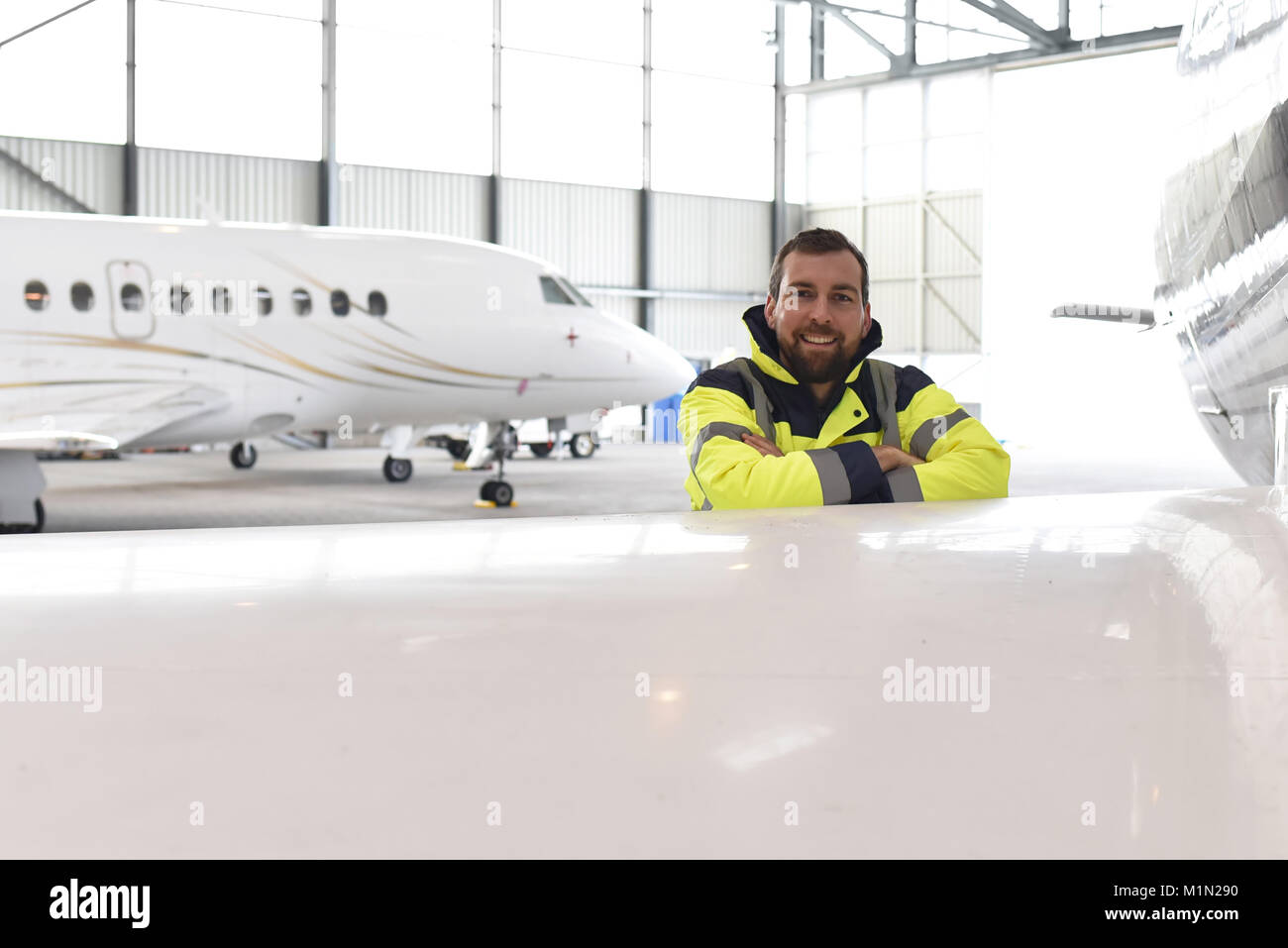 Portrait d'un mécanicien d'aéronefs dans un hangar avec des jets à l'aéroport - Contrôle de l'avion pour la sécurité et la fonction technique Banque D'Images