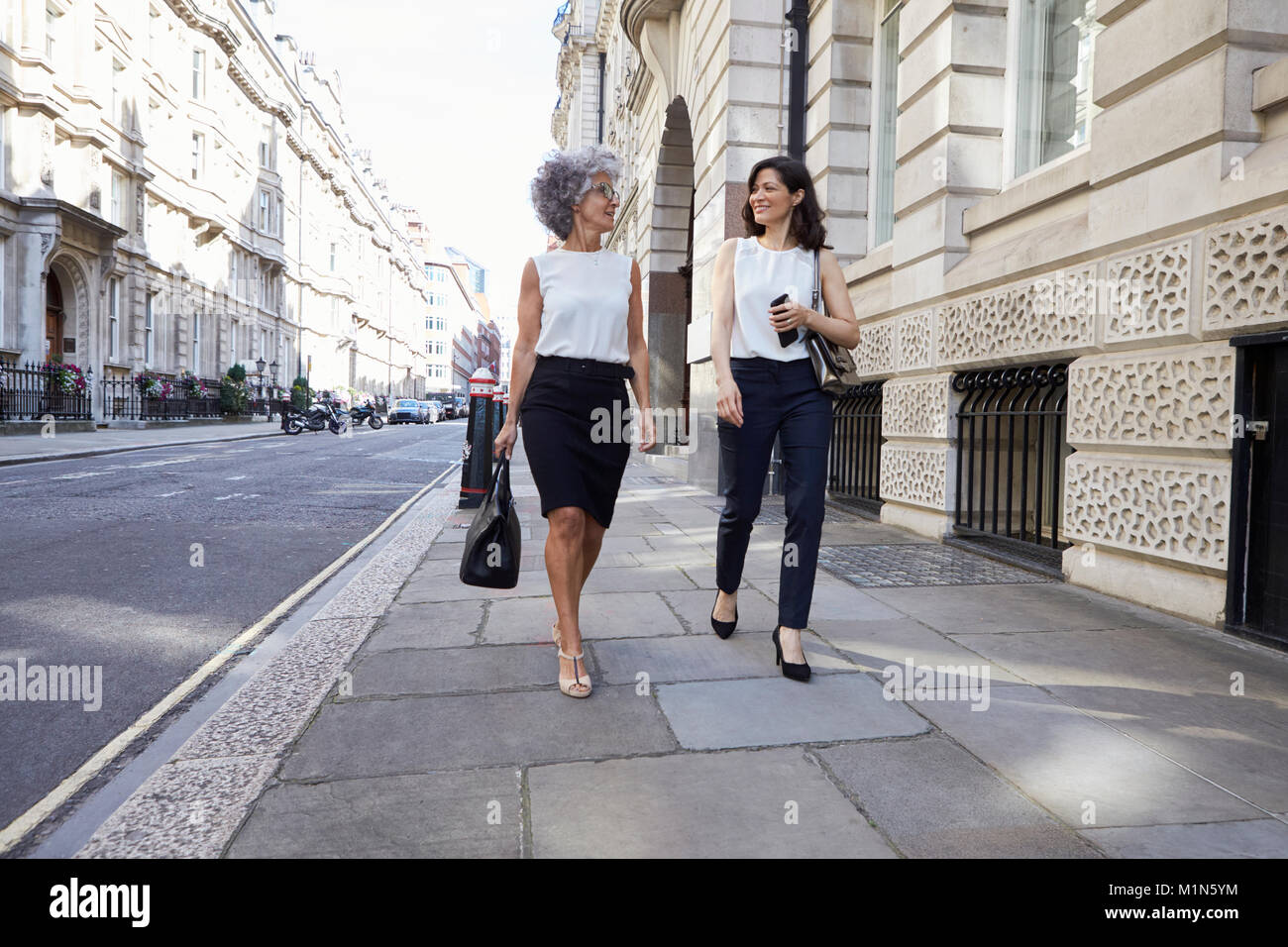 Deux collègues femmes marchant dans la rue parler Banque D'Images