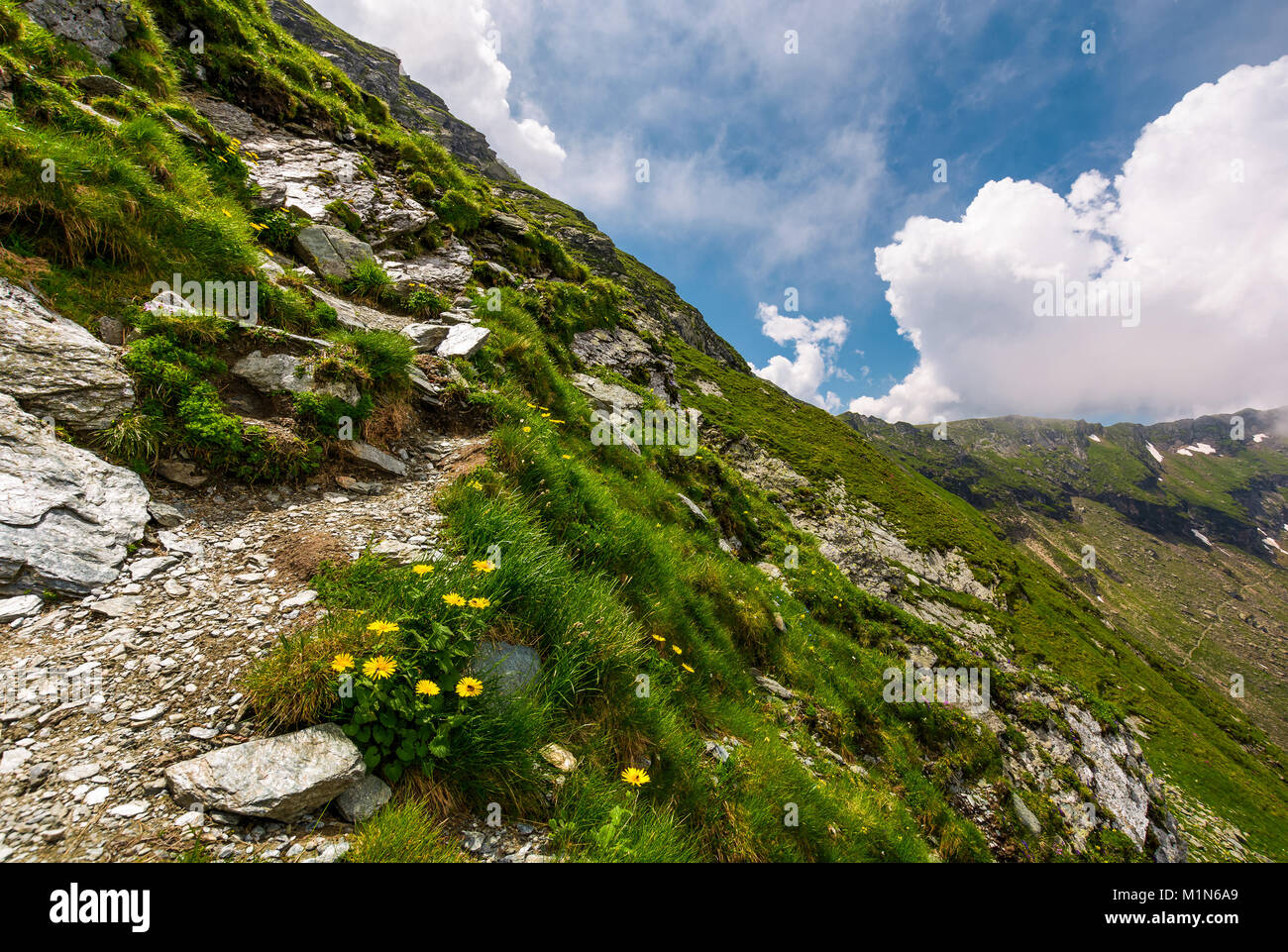 Chemin le long de la forte pente. beau paysage d'été avec des pierres on grassy hillside. Les nuages bas couvre le haut de la crête de la montagne Banque D'Images