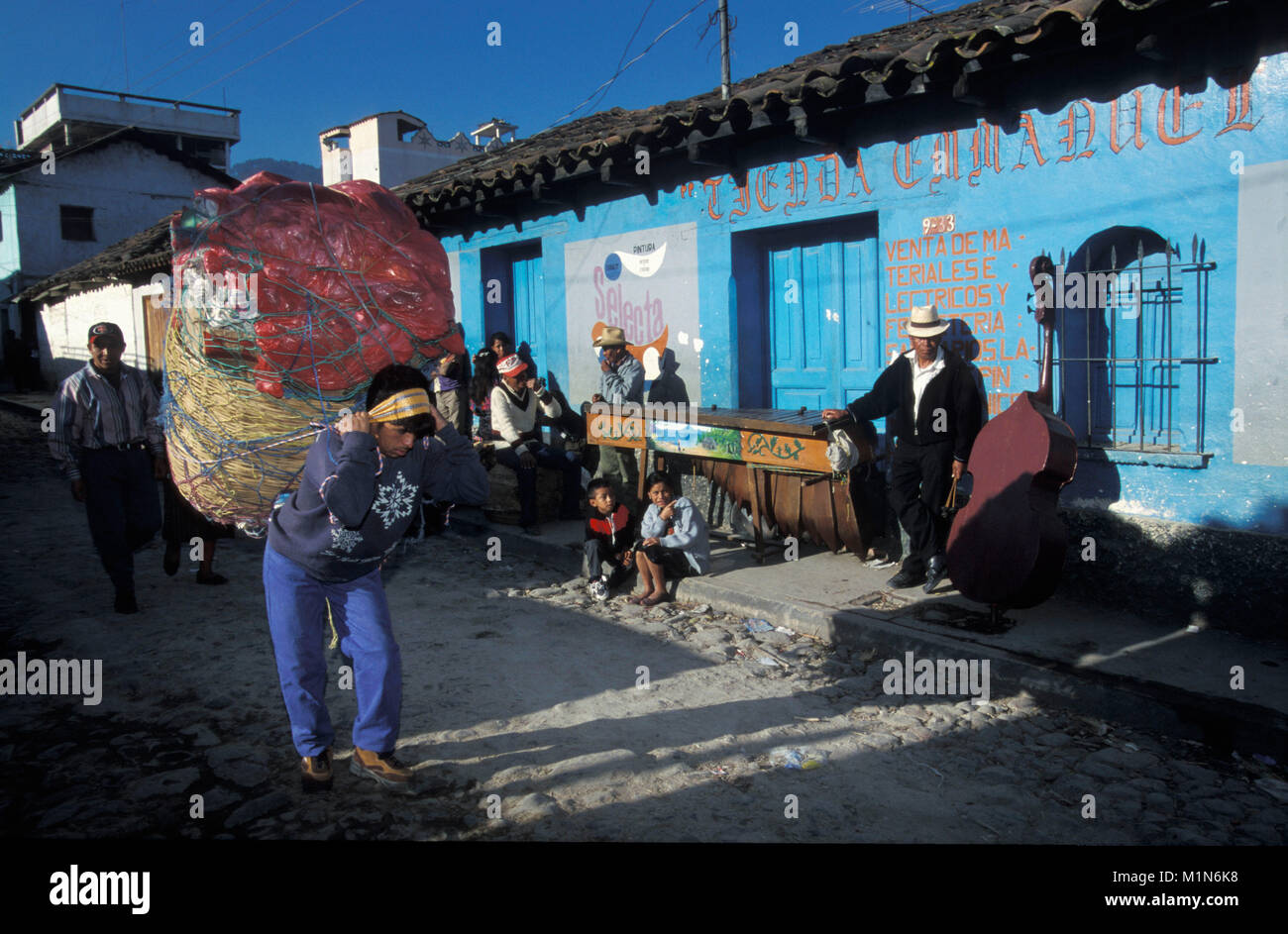 Le Guatemala. Chichicastenango. Homme transportant des marchandises sur le marché de rue. Contexte : bon musicien. A gauche : marimba (instrument typique du Guatemala). Banque D'Images