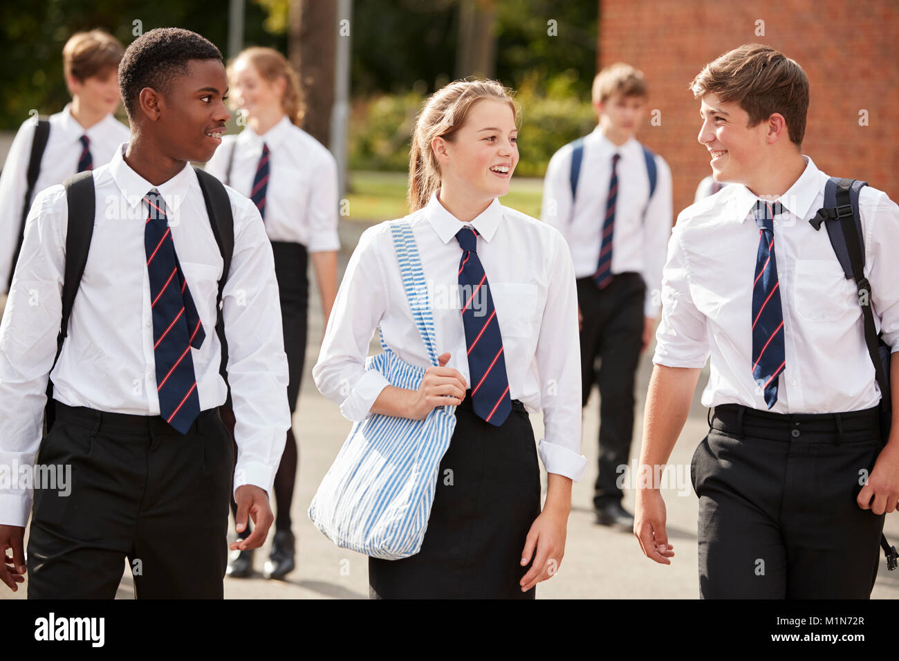 Groupe d'étudiants adolescents en uniforme à l'extérieur de bâtiments scolaires Banque D'Images