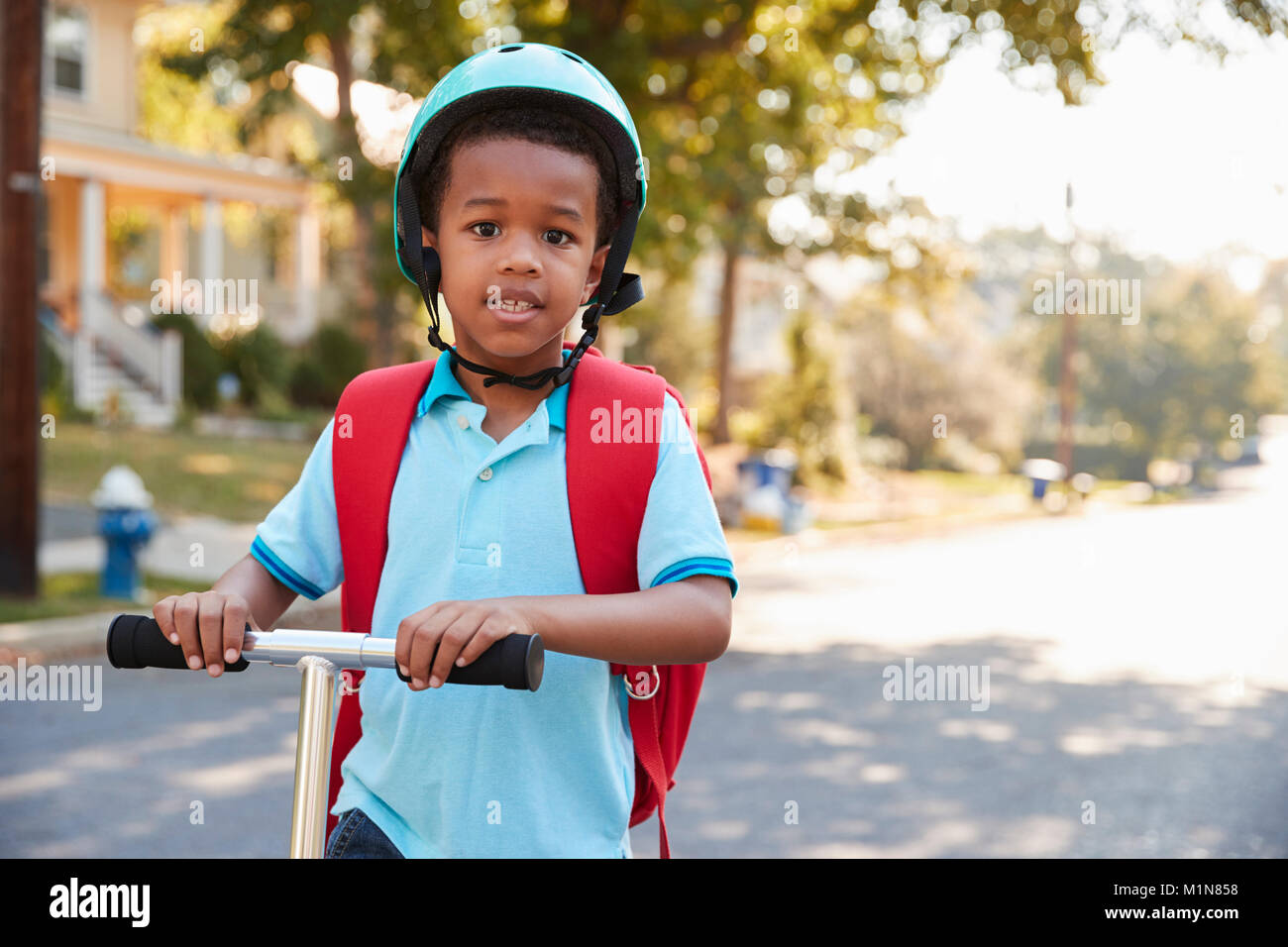 Young Boy Riding Scooter dans cette rue à l'école Banque D'Images