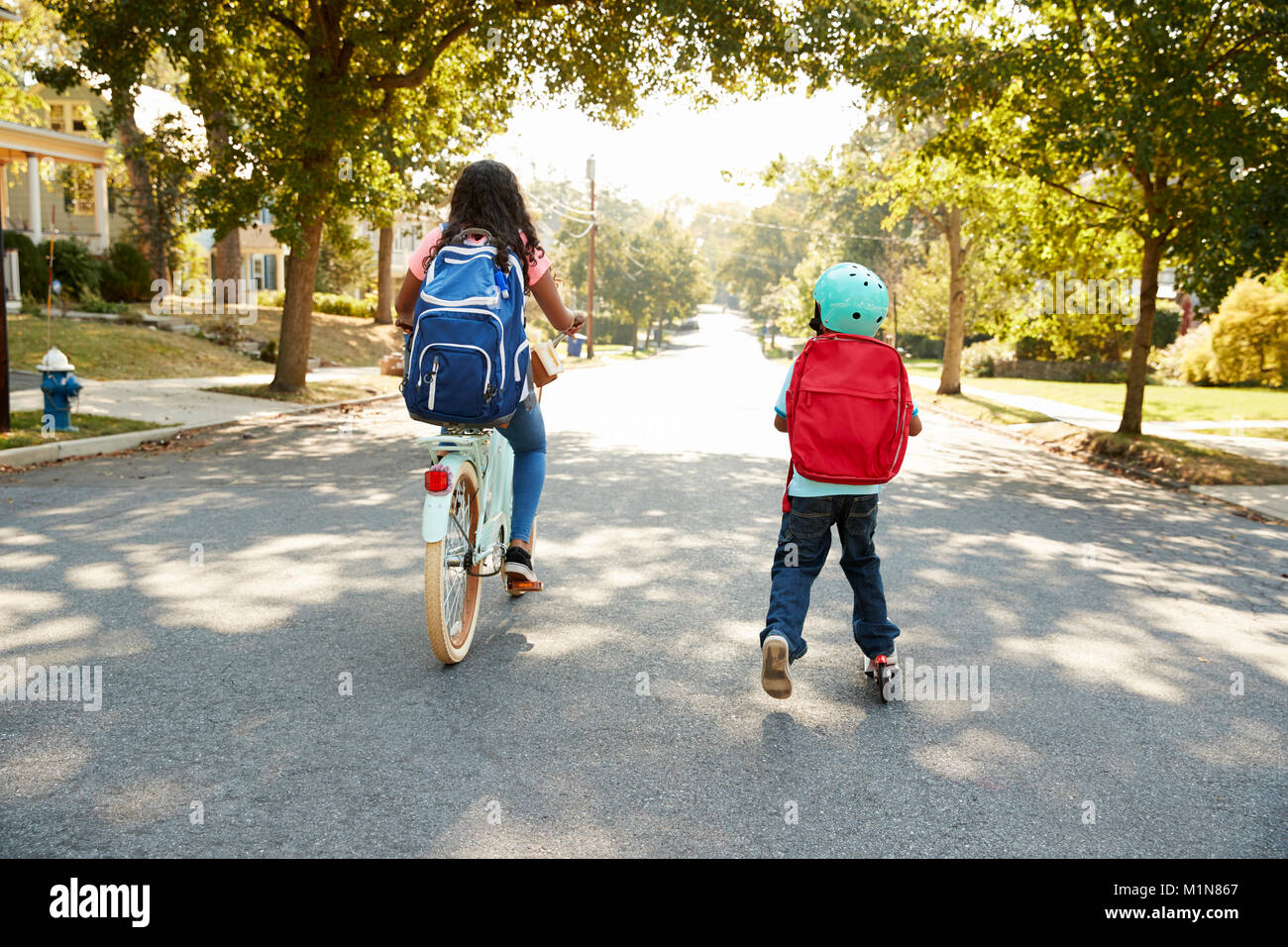 Avec sœur Frère Riding Scooter et vélo à l'école Banque D'Images