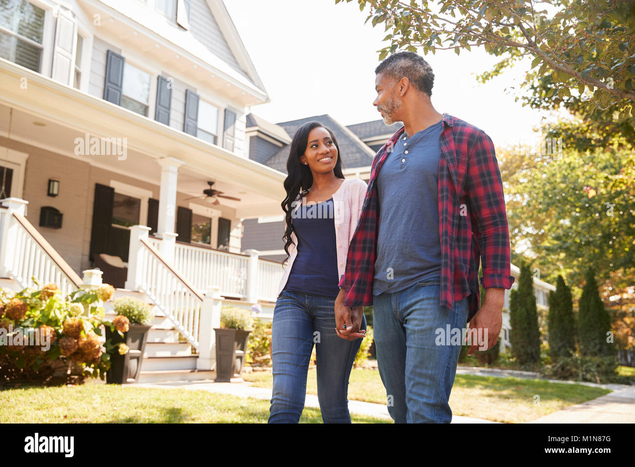 Couple en train de marcher le long de la rue de banlieue Holding Hands Banque D'Images