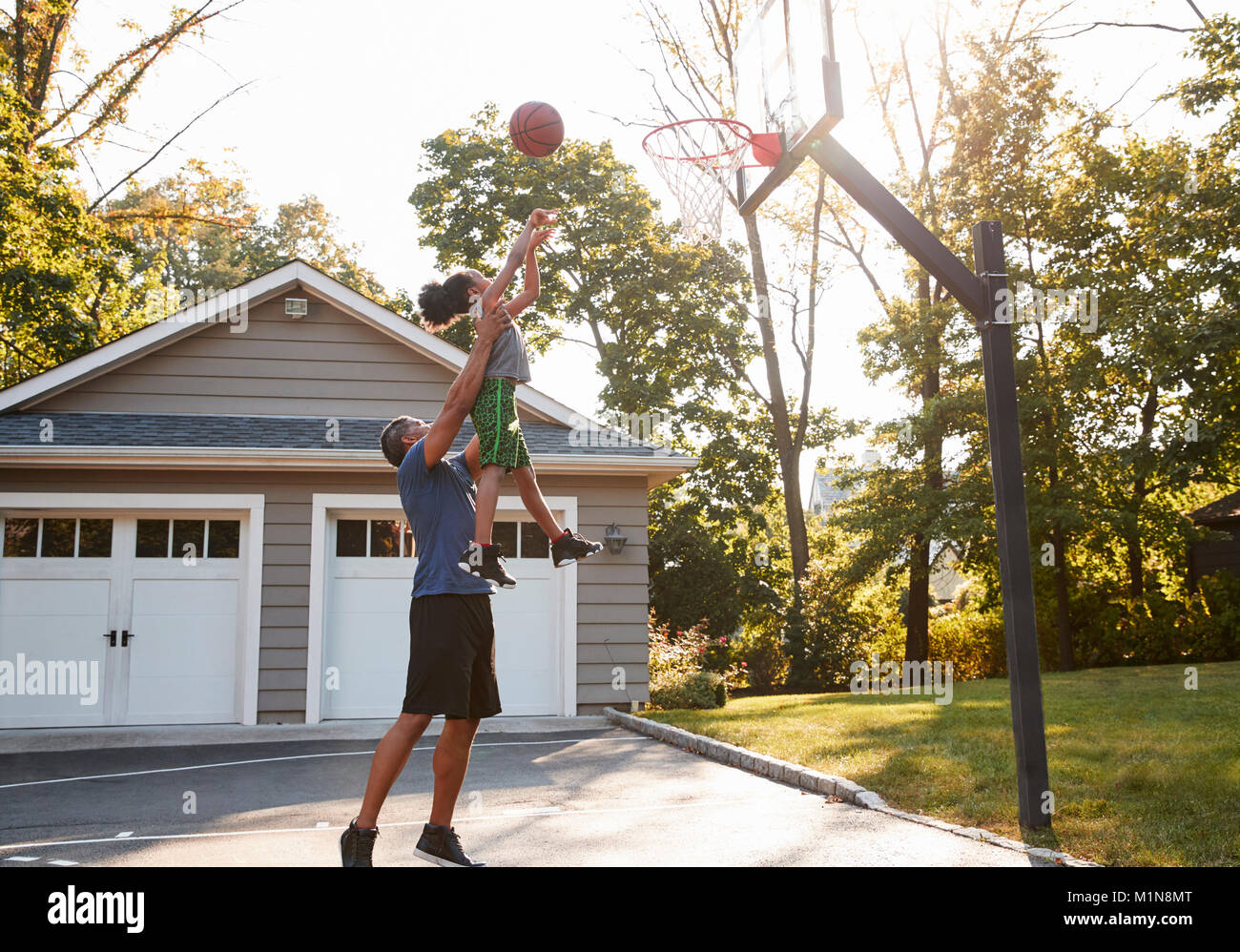 Père et fils jouer au basket-ball sur l'entrée à la maison Banque D'Images