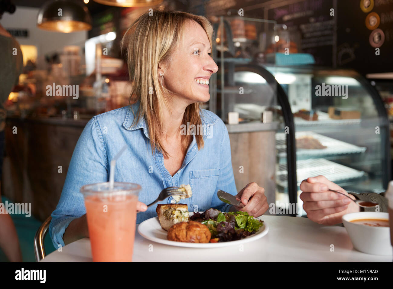 Femme dans un café assis à table en train de manger un déjeuner sain Banque D'Images