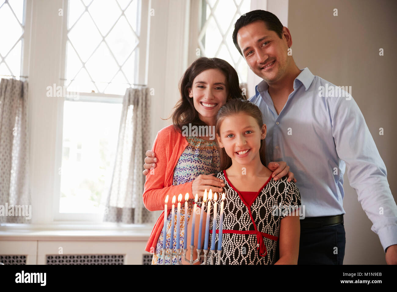 Fille de parents juifs et souriant, allumé des bougies sur la menorah Banque D'Images