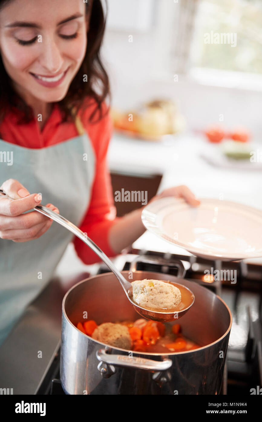 Femme balle matzon juif d'un pot de soupe sur la table de cuisson Banque D'Images