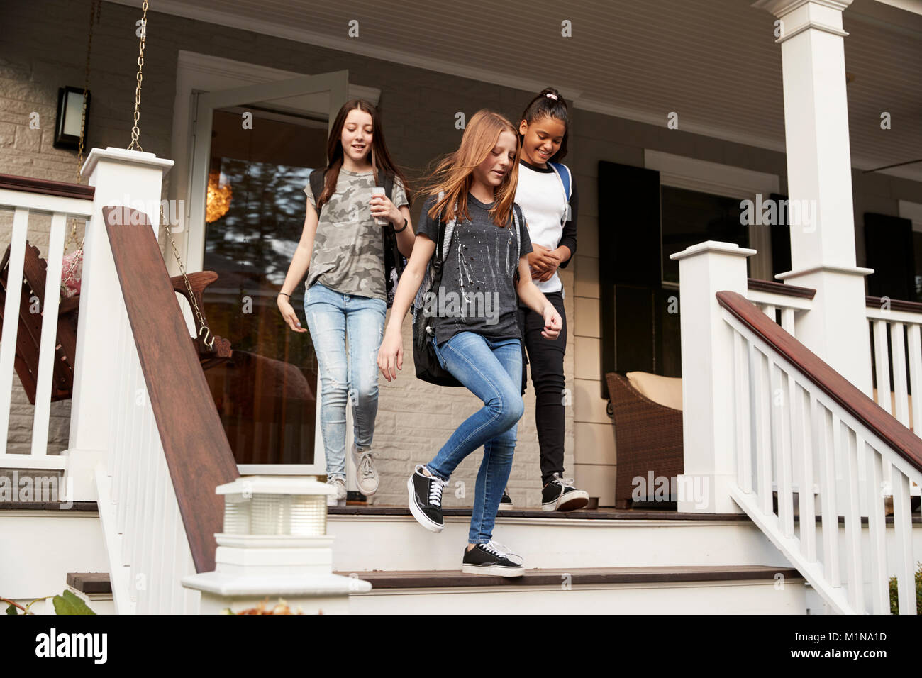 Trois adolescentes quitter maison avec sacs d'école Banque D'Images