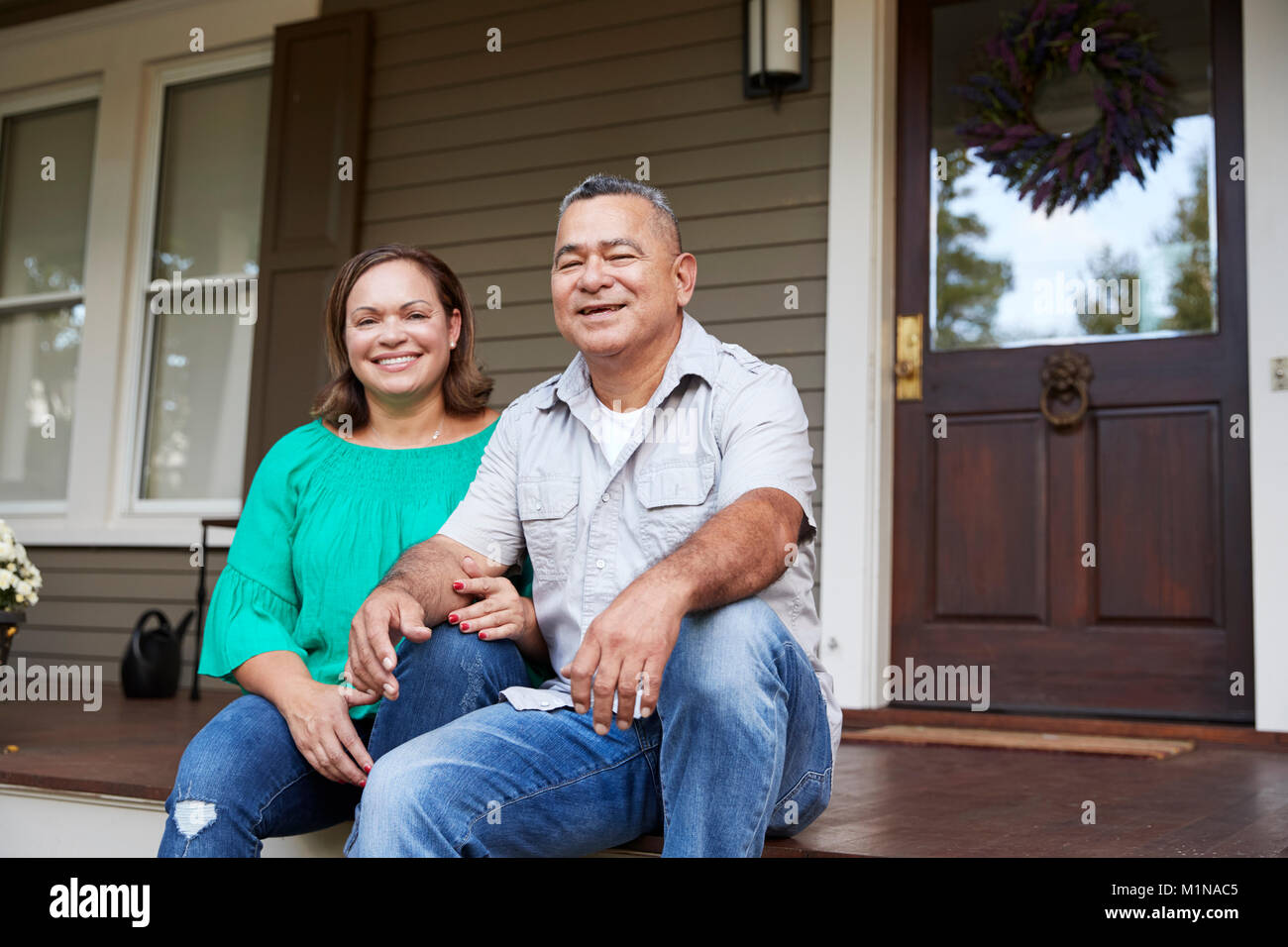 Portrait Of Smiling Senior Couple Sitting in front of their Home Banque D'Images