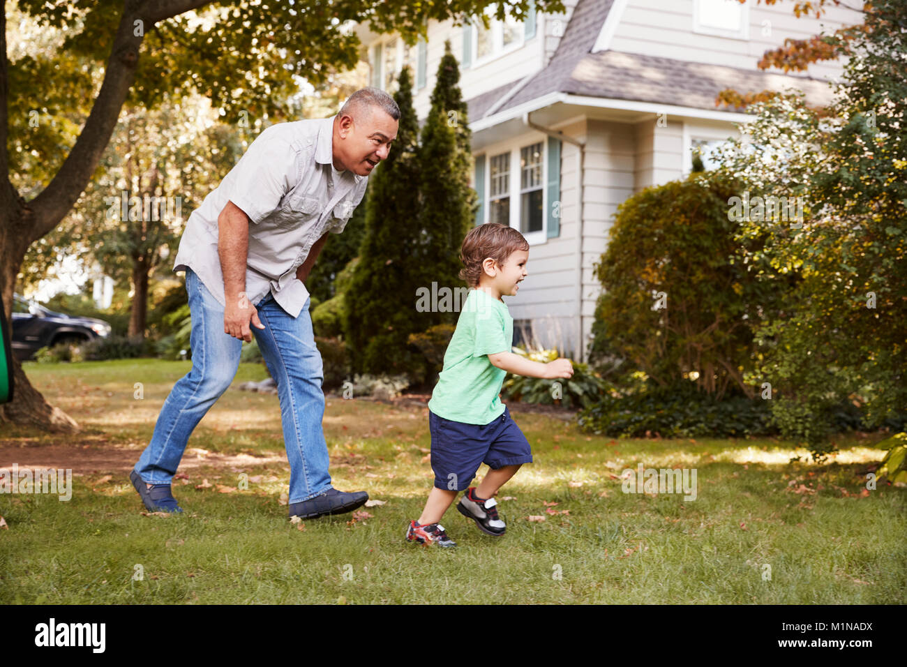 Grand-père jouant dans jardin avec petit-fils Banque D'Images
