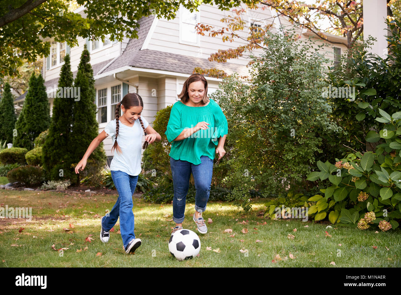 Grand-mère joue au soccer dans jardin avec petite-fille Banque D'Images