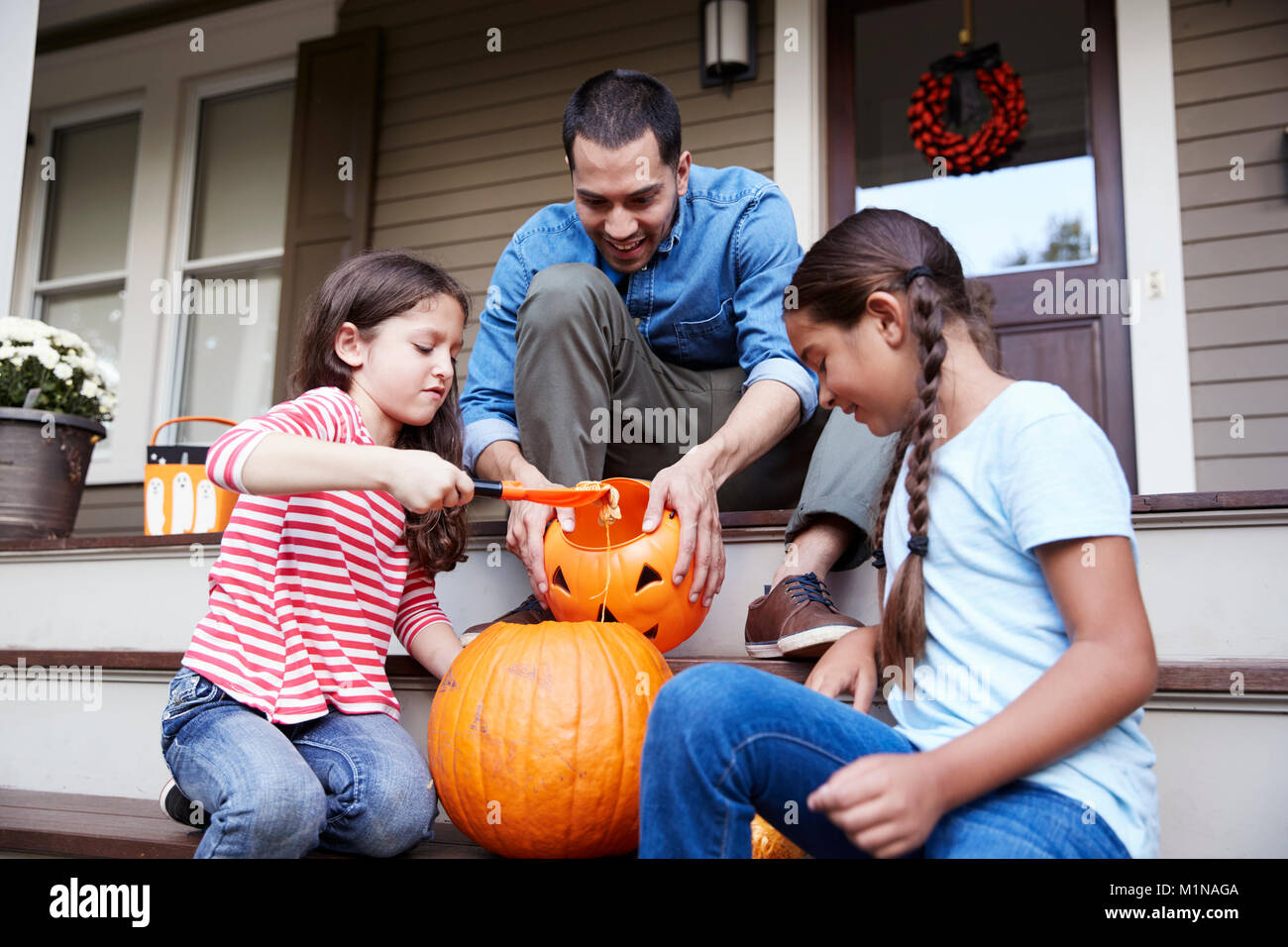 Père et filles Halloween Pumpkin Carving sur les étapes de la chambre Banque D'Images