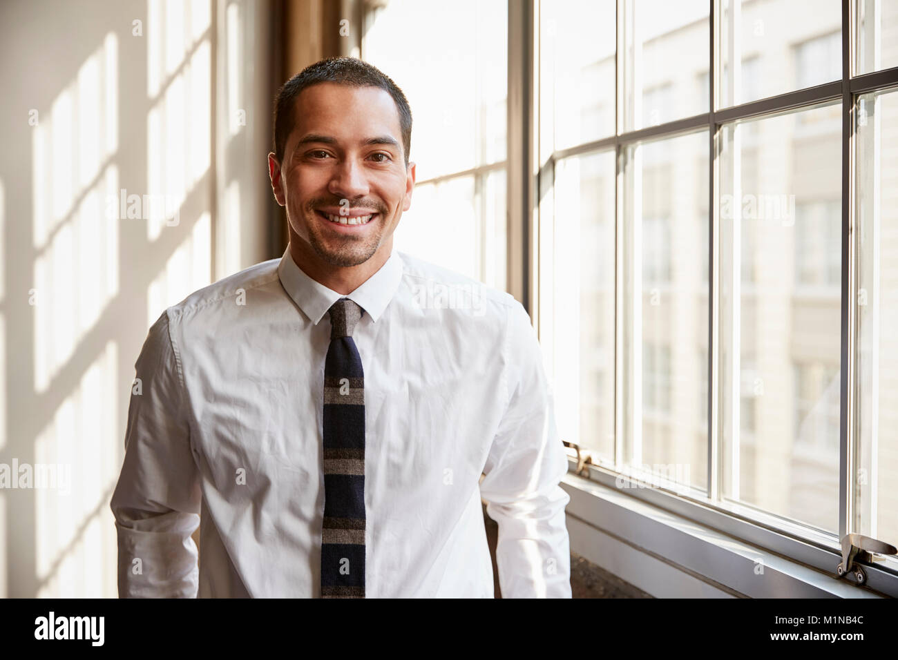 Young Hispanic businessman smiling to camera, Close up Banque D'Images