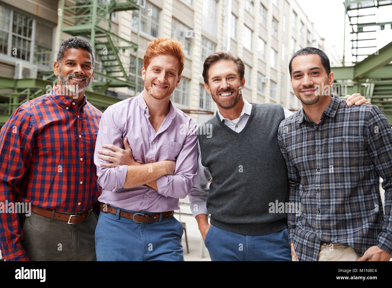 Quatre collègues masculins à l'extérieur de l'appareil photo en souriant Banque D'Images