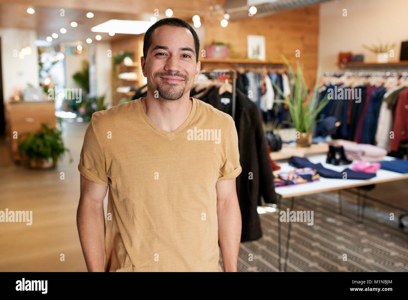 Smiling young Hispanic man standing dans un magasin de vêtements Banque D'Images