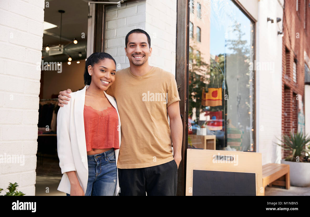 Young Hispanic couple smiling to camera en dehors de leur shop Banque D'Images