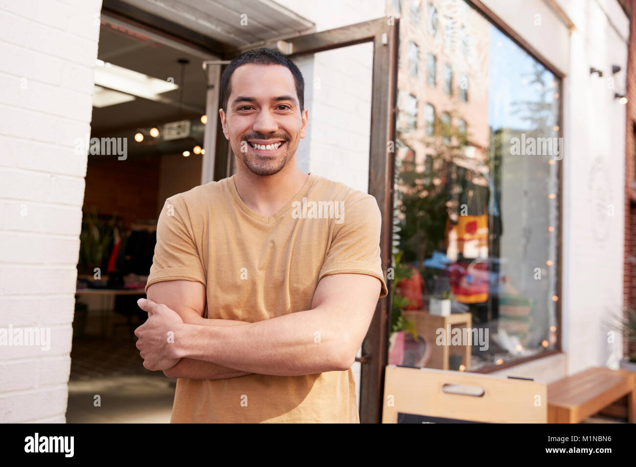 Young Hispanic shop owner smiling to camera à l'extérieur de son magasin Banque D'Images
