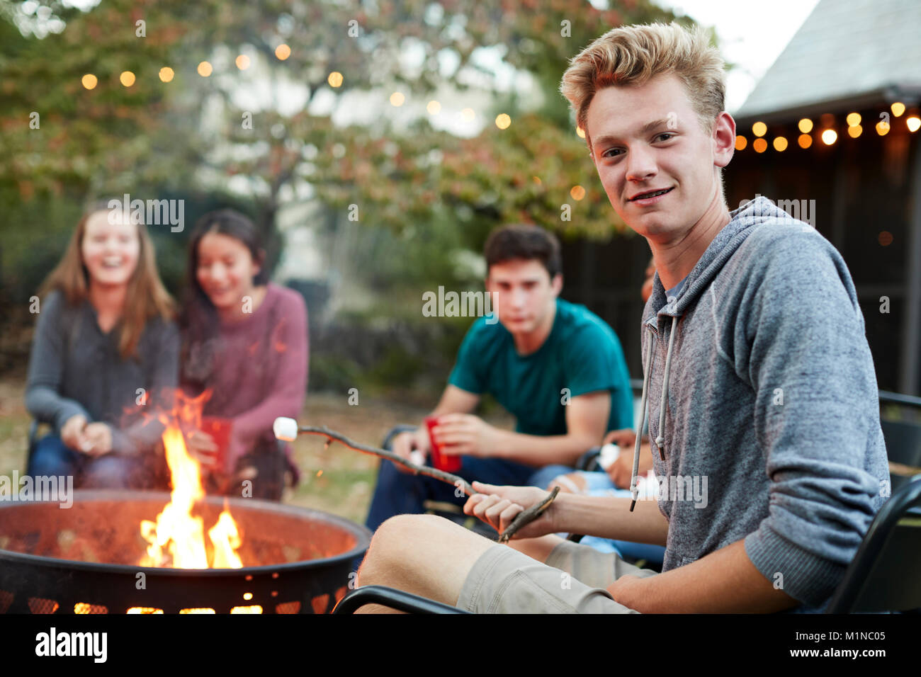 Teenage boy with friends toasting guimauve un foyer Banque D'Images