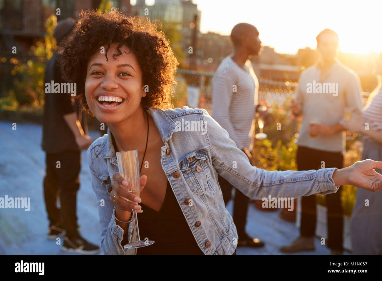 Young woman dancing at a rooftop party smiling to camera Banque D'Images