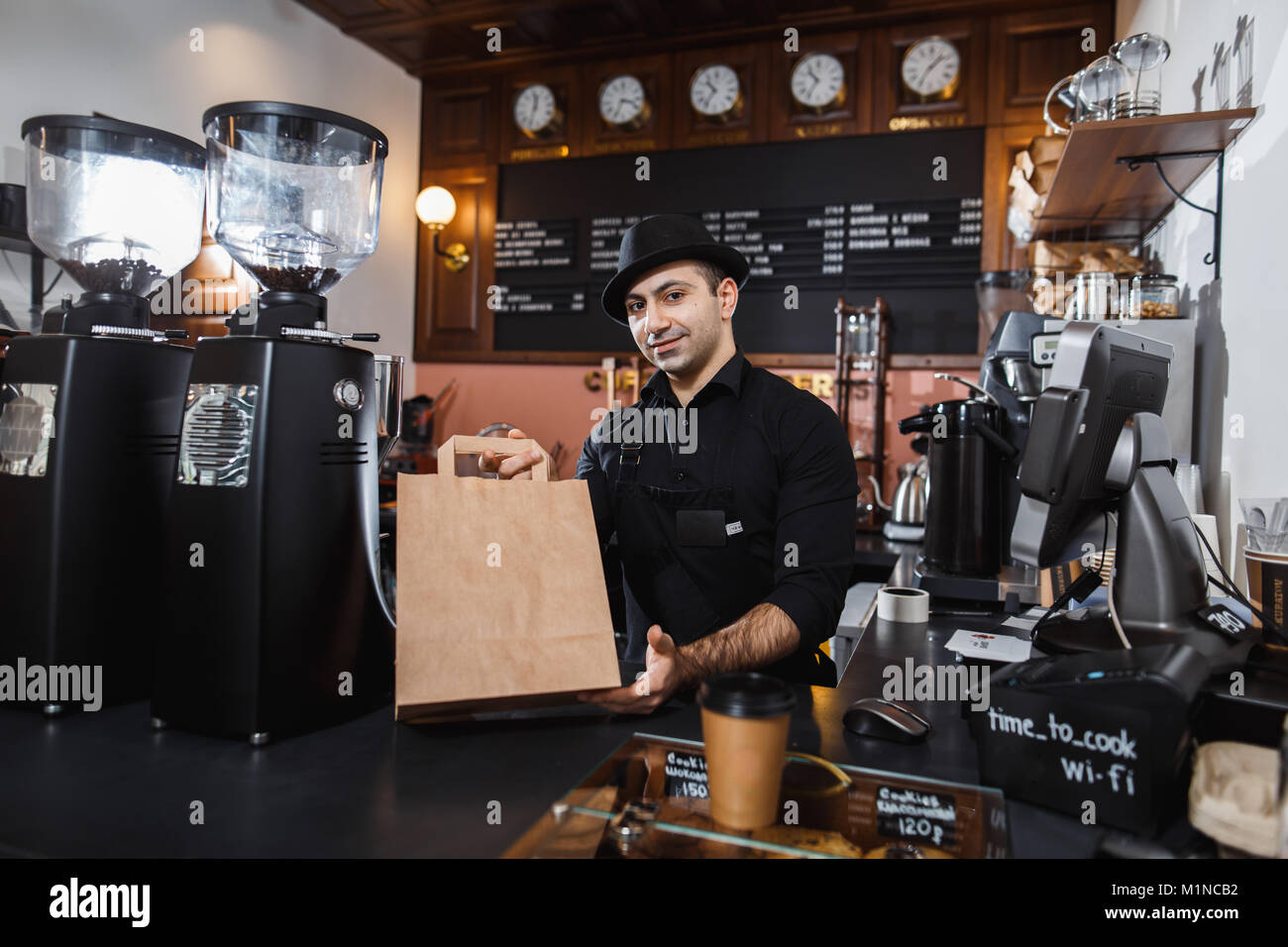 Café barista vente mâle positif pour un consommateur dans un café. Banque D'Images