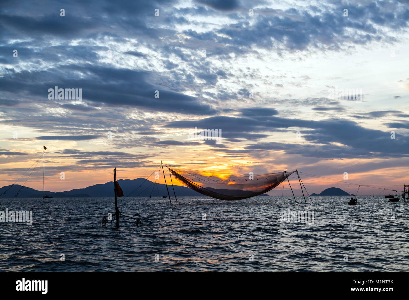 Le lever du soleil sur un filet de pêche suspendu dans la mer, à l'entrée de la rivière Thu Bon, près de Hoi An, Vietnam Banque D'Images