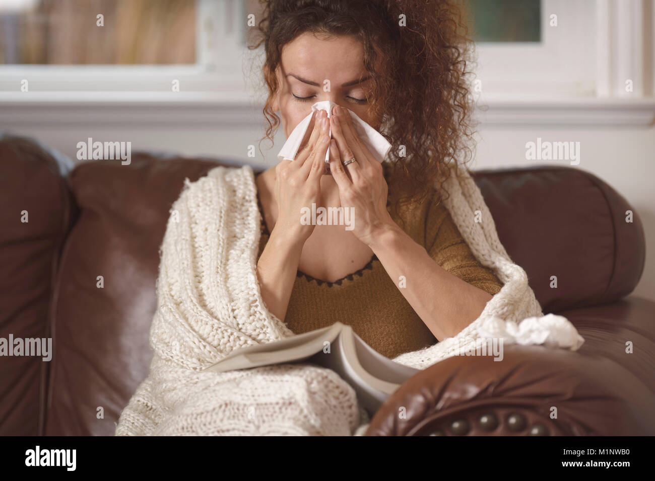Une femme malade souffle son nez dans un mouchoir en papier, souffle son  nez et tient un thermomètre. Une femme caucasienne a un nez qui coule et un  rhume. Mer Photo Stock -
