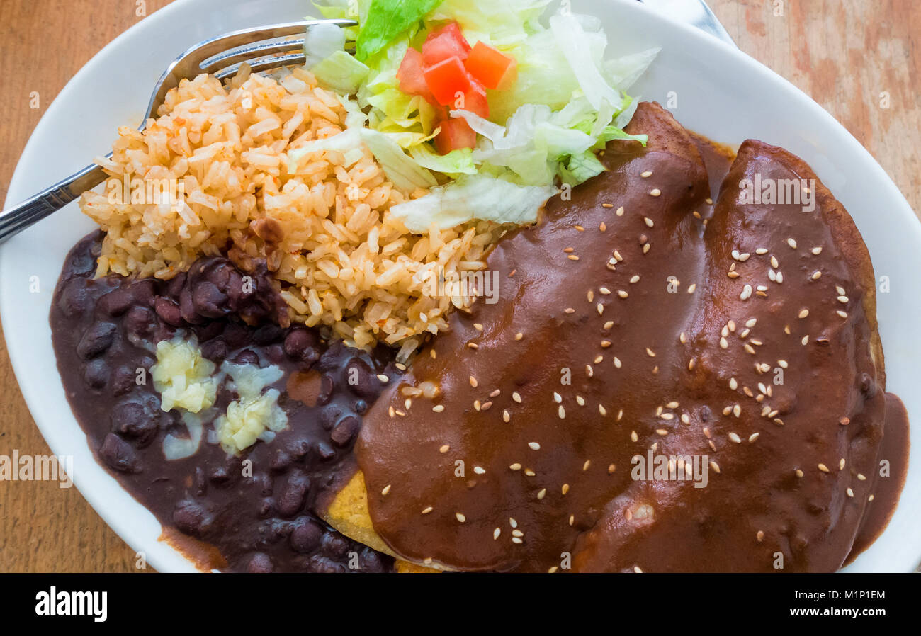 Enchiladas au poulet Mole Poblano, avec les haricots noirs, le riz brun et salade Banque D'Images