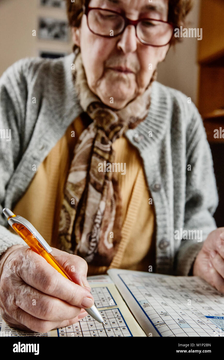 Les cadres supérieurs s'assied à la table à la maison et de résoudre des casse-tête Sudoku,,mots croisés,Cologne, Rhénanie du Nord-Westphalie, Allemagne Banque D'Images