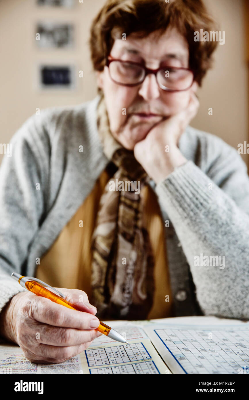 Les cadres supérieurs s'assied à la table à la maison et de résoudre des casse-tête Sudoku,,mots croisés,Cologne, Rhénanie du Nord-Westphalie, Allemagne Banque D'Images