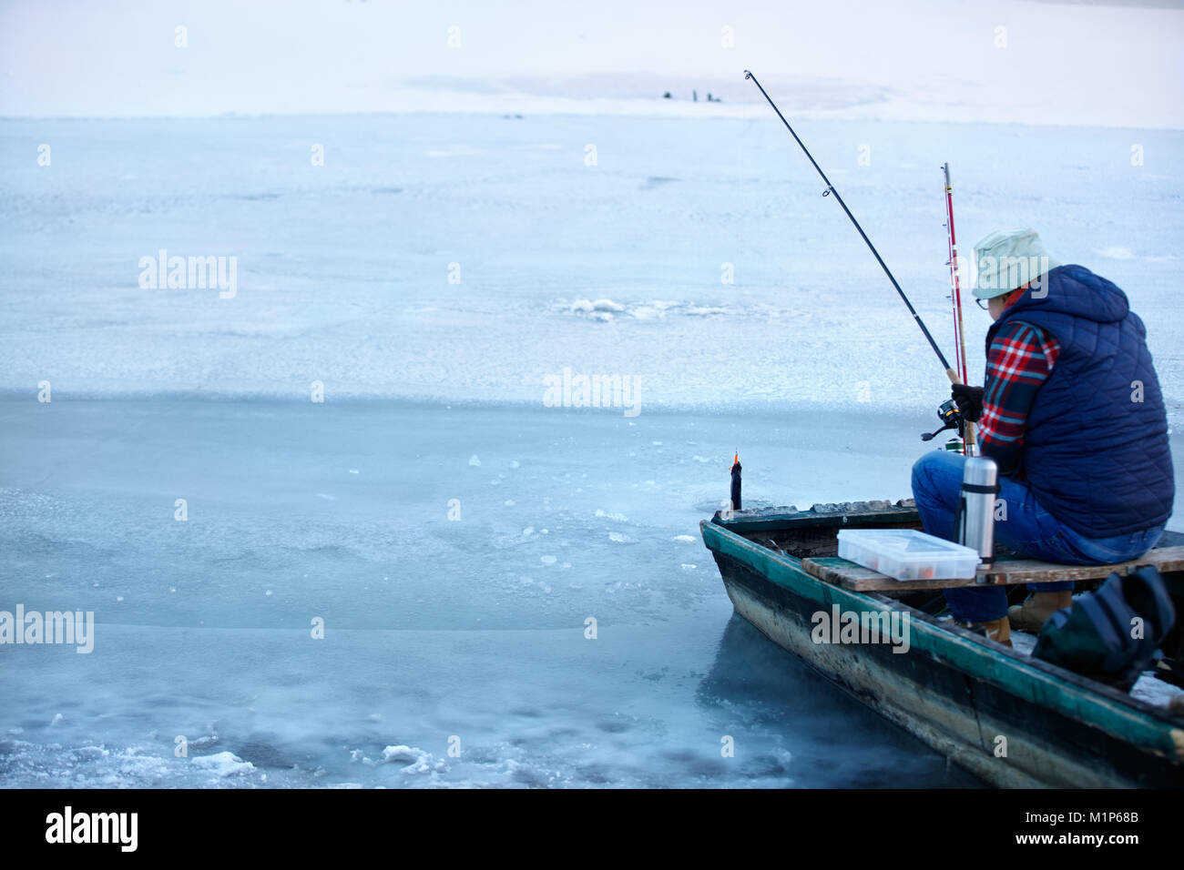 Vue arrière du bateau pêcheur en maturité alors que la pêche en rivière gelée en hiver Banque D'Images