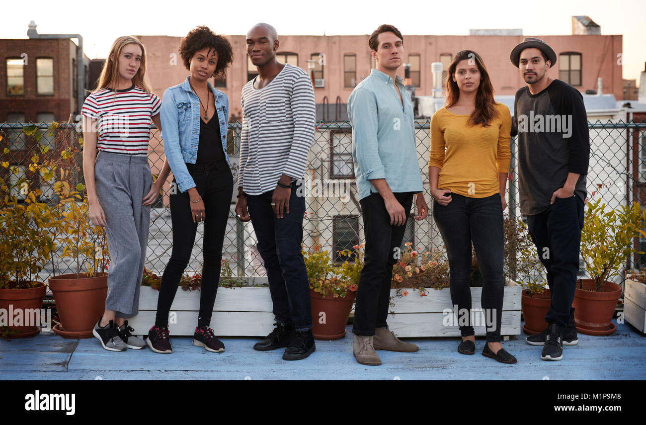Six amis adultes debout ensemble sur toute la longueur, sur le toit Banque D'Images