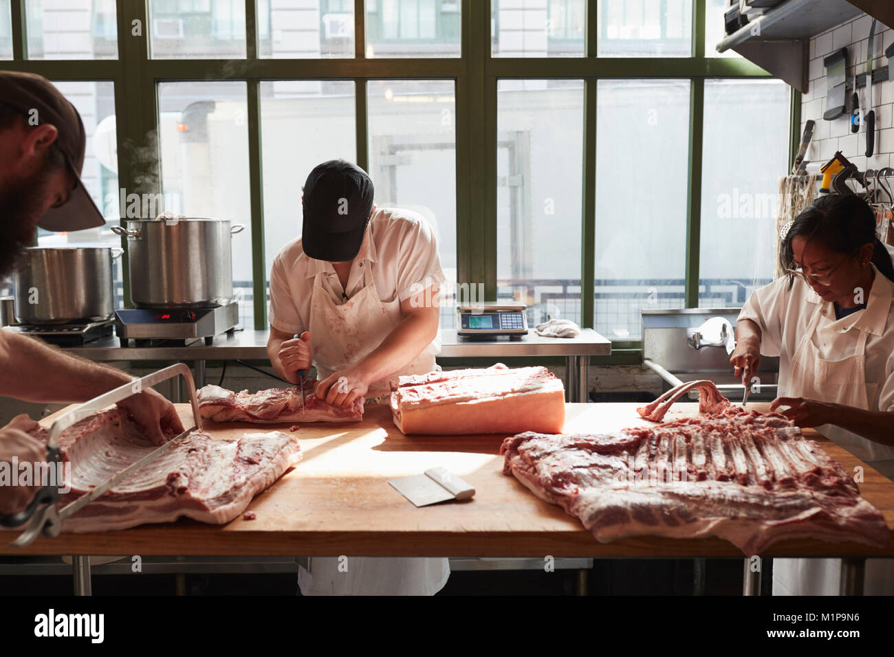 Trois bouchers la préparation de porc pour une boucherie Banque D'Images
