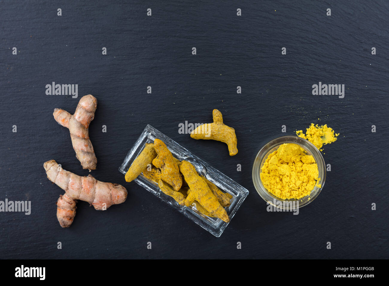 Fruits frais et secs ou curcuma curcumine racines et poudre sur fond noir. Vue de dessus, copy space Banque D'Images