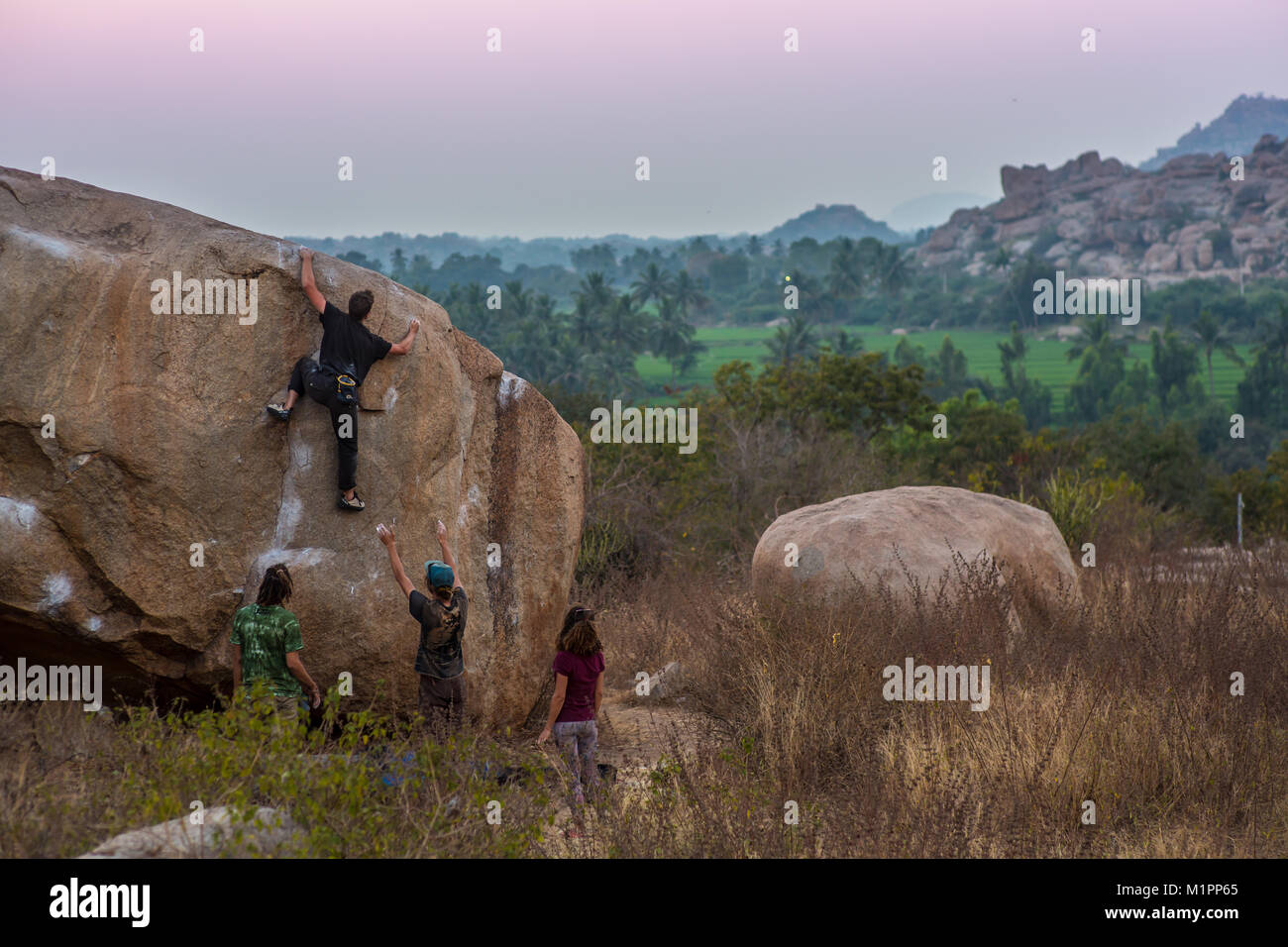 Un groupe de personnes bouldering in Hampi, Inde au coucher du soleil. Banque D'Images