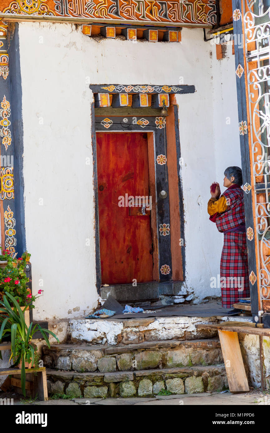 Bumthang, Bhoutan. Femme en prière dans l'Jambey Lhakhang temple et monastère. Banque D'Images