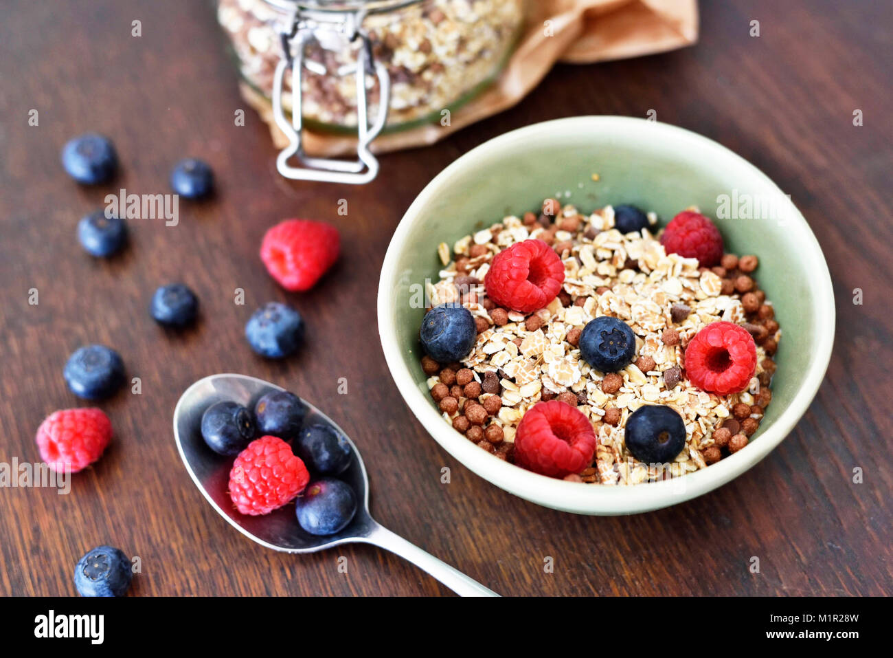 Scène avec petit déjeuner dans un bol de céréales et fruits frais. Le petit-déjeuner ou bol de céréales avec les framboises et les bleuets. Table en bois et d'une saine alimentation mauvaise. Banque D'Images Scène avec petit déjeuner dans un bol de céréales et fruits frais. Le petit-déjeuner ou bol de céréales avec les framboises et les bleuets. Table en bois et d'une saine alimentation mauvaise. Banque D'Images