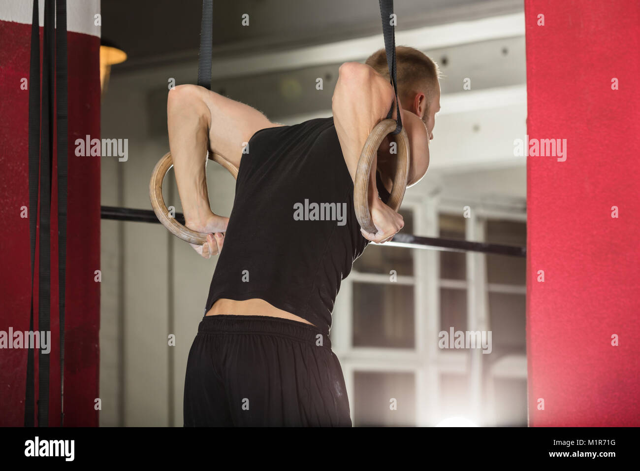 Jeune homme en tirant sur les anneaux de gymnastique dans la salle de sport Banque D'Images