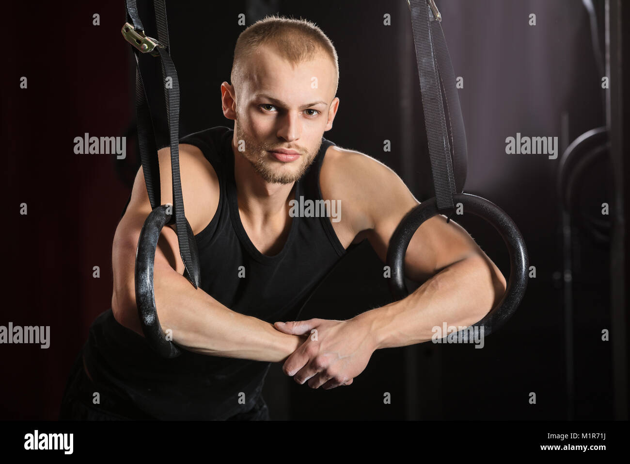 Portrait d'une jeune athlète masculin avec anneaux de gymnastique dans la salle de sport Banque D'Images