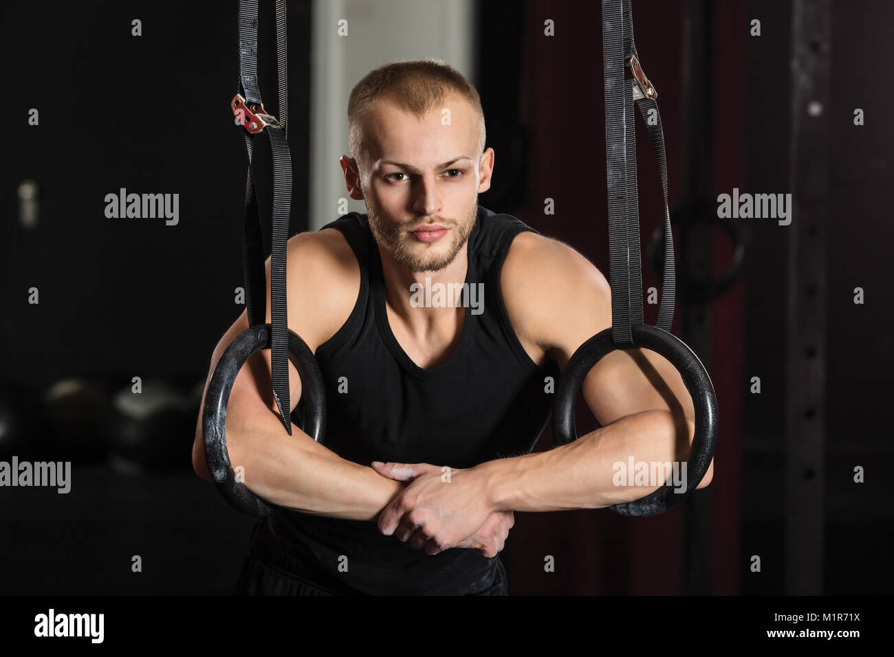 Portrait d'une jeune athlète masculin avec anneaux de gymnastique dans la salle de sport Banque D'Images