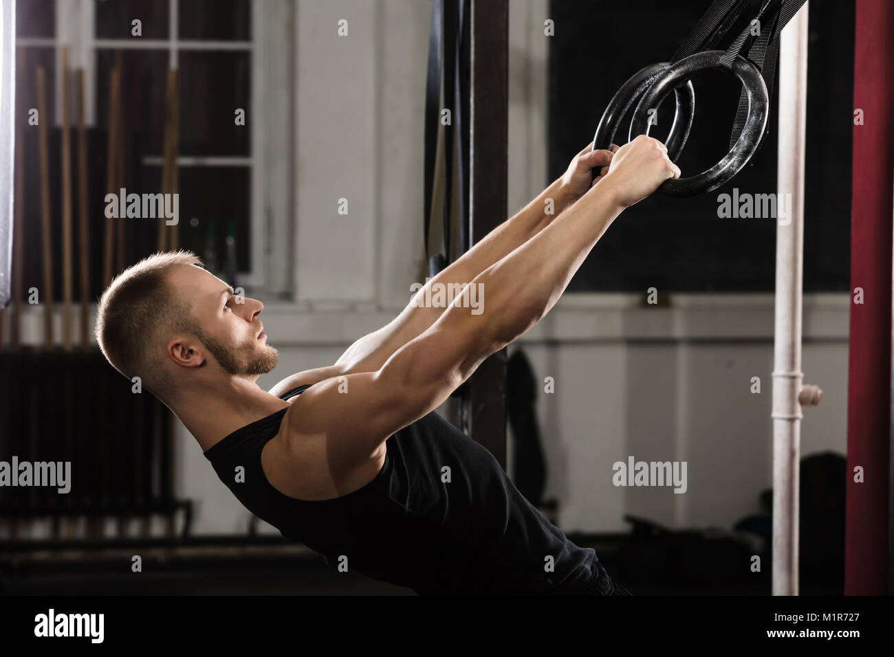 L'exercice de l'homme remise en forme sur les anneaux de gymnastique dans la salle de sport Banque D'Images