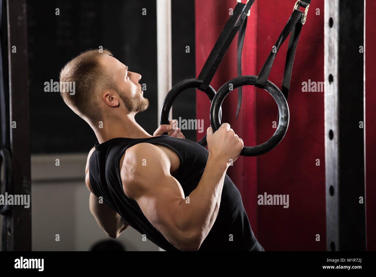 Homme fitness en tirant sur les anneaux de gymnastique dans la salle de sport Banque D'Images