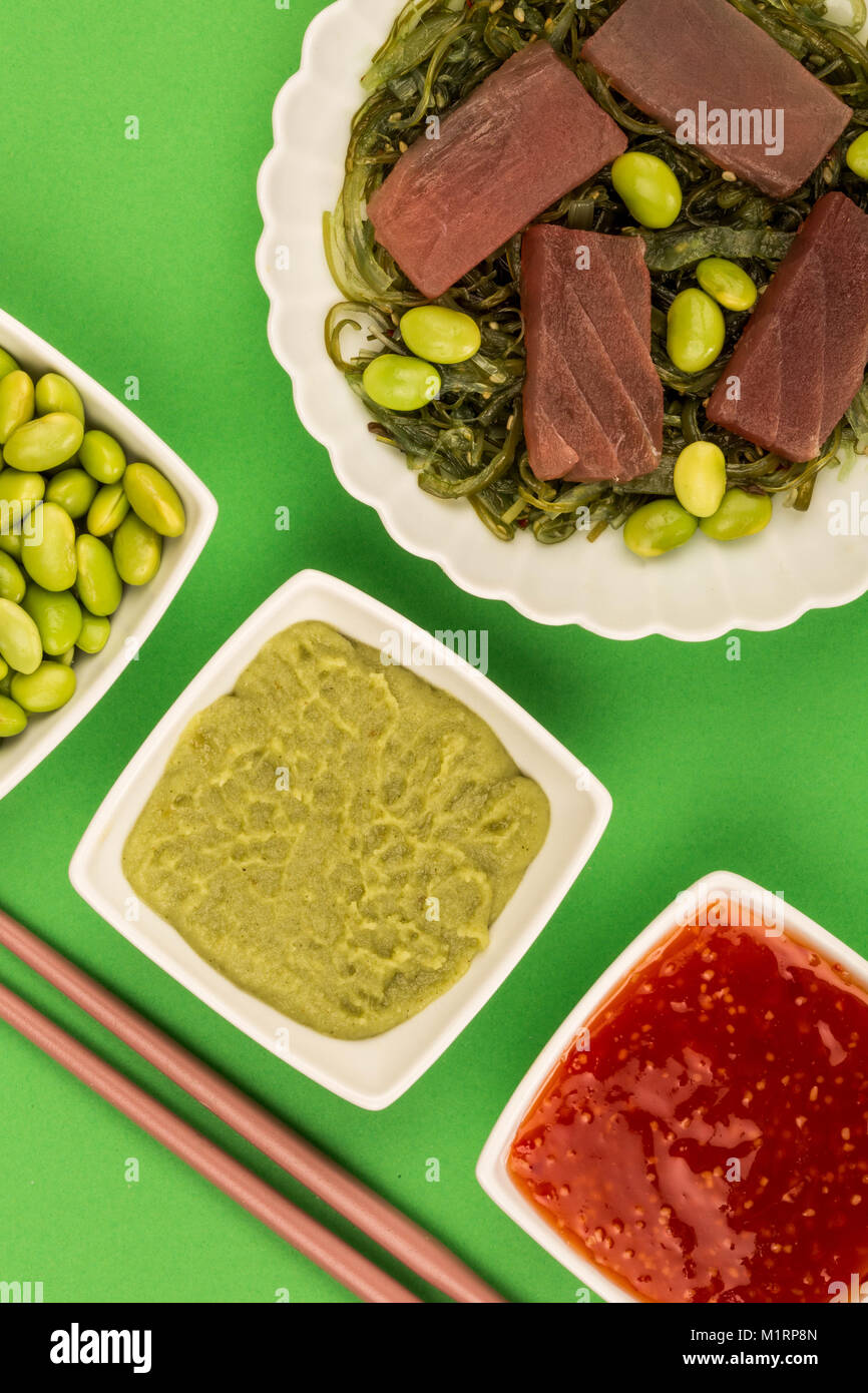 De style japonais, sashimi de thon cru sur un lit d'algues marinées avec Edamame Beans sur fond vert Banque D'Images