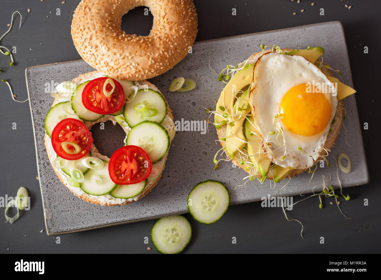 Sandwichs sur bagels aux oeufs, avocat, fromage, tomate, concombre, pousses de luzerne Banque D'Images