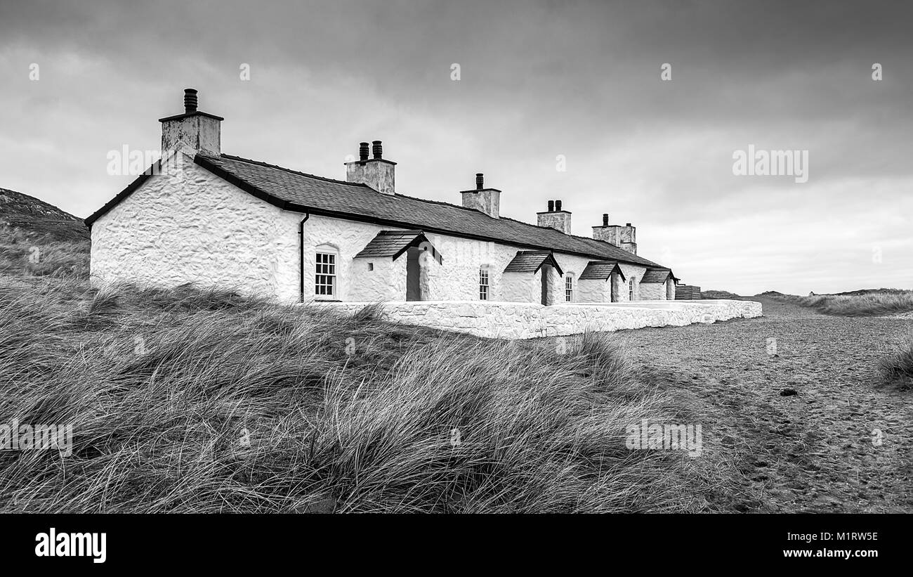 Une photographie en noir et blanc d'une rangée de vieilles maisons de pêcheurs sur la plage Banque D'Images