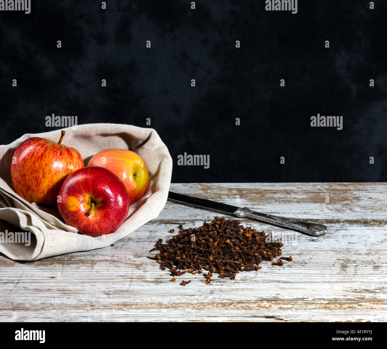 Fiche de clous de girofle et d'Apple sur une vieille table en bois blanc. Fond sombre non uniforme avec de l'espace libre pour le texte Banque D'Images