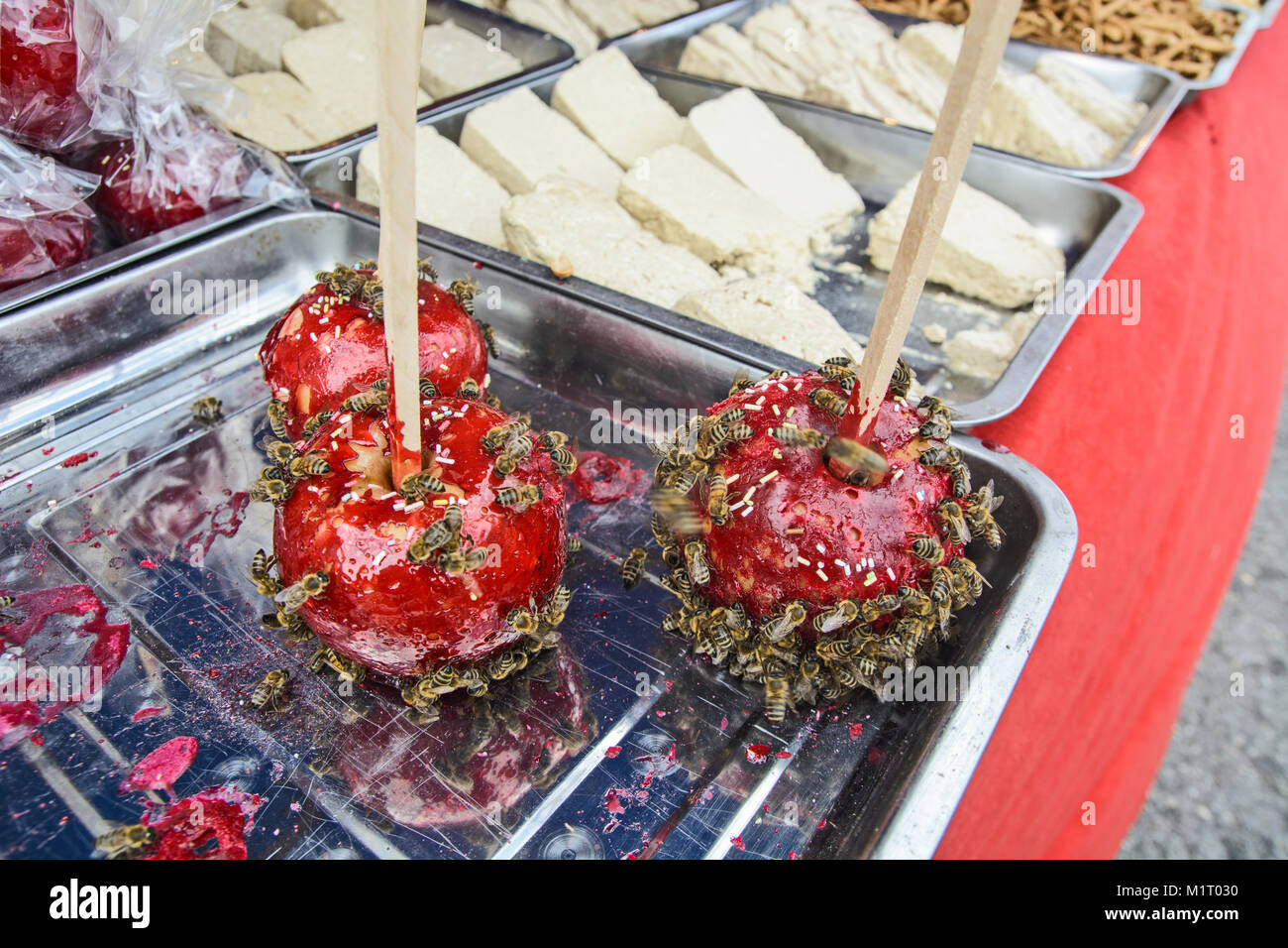 Pommes rouges sucrés au sucre glacé et abeilles sur eux. Banque D'Images