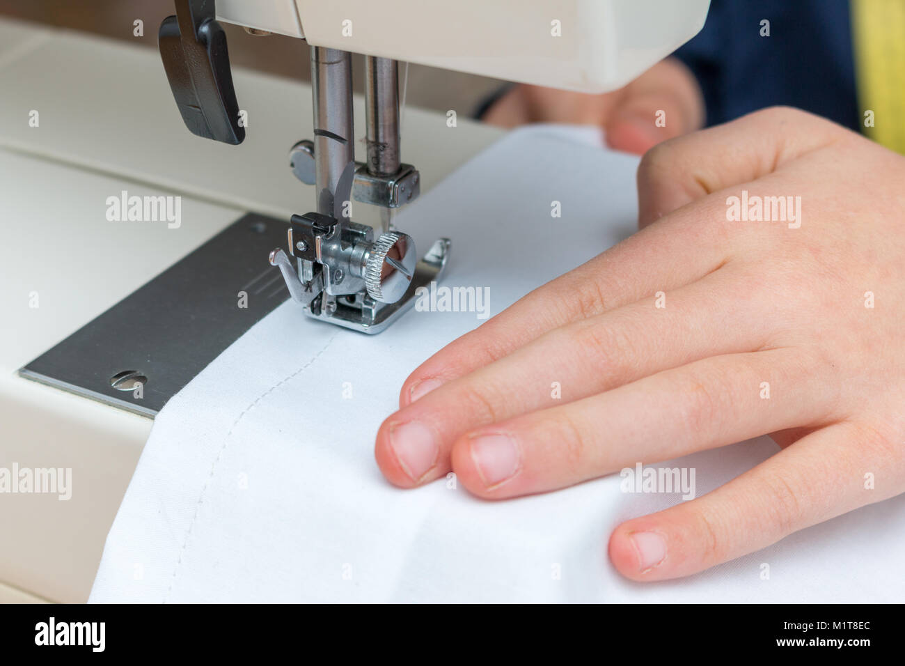 Close-up of a childs manuellement en tirant un livre blanc textil à travers une machine à coudre Banque D'Images