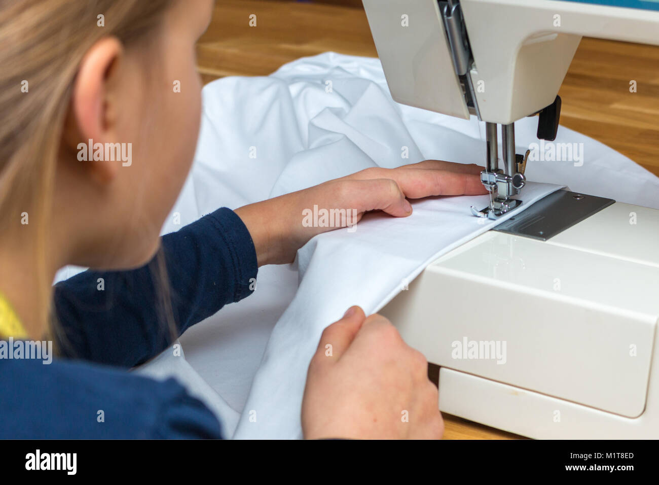 Une fillette de 8 ans est une couture blanc textil Banque D'Images